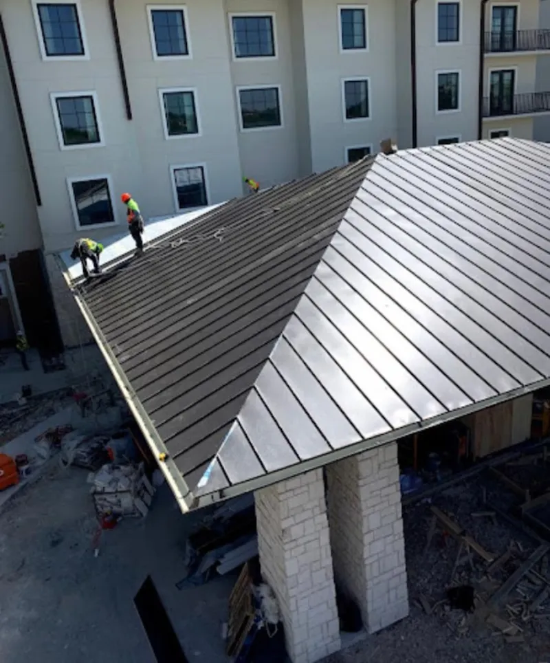 Crew installing standing seam metal roof panels on a commercial project in Ballston